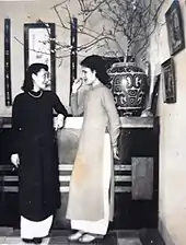 Two women in áo dài chatting.