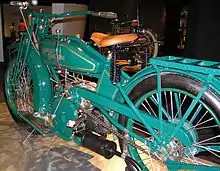A pristine motorcycle of 1919, painted green with a v-twin engine and footboards.