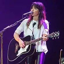 A photograph of Tunstall smiling, looking away from the camera. A microphone is positioned in front of her face.