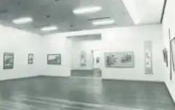 An archival black-and-white photo of rows of paintings hung in a white-cube gallery space
