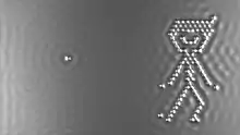 An image of a small boy on the right made out of silvery dots against a gray background, with a single dot on the left