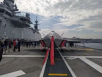 The Baykar MIUS Kızılelma on the flight deck of TCG Anadolu, anchored at the port of Karaköy on the Golden Horn in Istanbul.