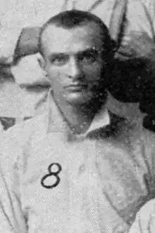 A portrait of a man wearing a light baseball jersey.