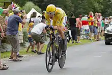 Bradley Wiggins riding a time trial bicycle wearing yellow cycling clothing