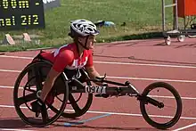 White woman with a red and white top in a black wheelchair.