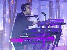A man with glasses and headphones playing a keyboard