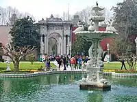 Interior façade of the Gate of the Treasury (Hazine-i Hassa Kapısı) near Dolmabahçe Clock Tower, which is seen in the background, outside the walls, at left.