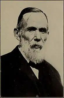 Black-and-white photograph of John Arbuckle, with a white beard and short hair, in a suit with a bow tie.