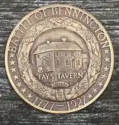 A bronze medal, bearing the legends, "BATTLE OF BENNINGTON" and "1777-1927" and 14 stars. This surrounds a wreath with ribbons with the names of battle participants such as "ALLEN". Within the wreath is a building, and the inscription "FAY'S TAVERN".