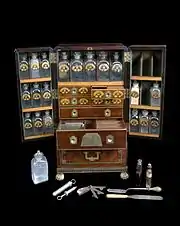A medicine chest, winged front, from Reece's Medical Hall, Piccadilly, with 30 painted glass bottles and 4 drawers, 5 confection glasses, 1 probang, 3 boxes, 1 plaster spreader, 1 seal, 1 spatula, 1 bowl, 1 pill tile, 1 fleam, 1 lancet, 2 syringes, 4 visiting cards, 1 receipt and engraved plate, circa 1805