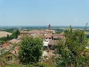 Photo shows village rooftops in the foreground. In the background, it can be seen that the surrounding country is all at lower elevation.
