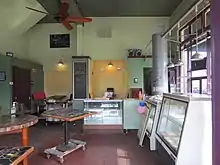 Photograph of the interior of a restaurant, with tables and chairs, as well as a counter and display cases