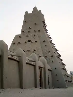 A mud building with wooden spikes sticking out of it (from Human history)