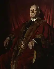 Man seated and wearing red fur trimmed robes and chain of office