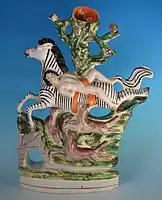 Staffordshire figure group and spill vase, circa 1860, where the artist has depicted a zebra, and wolves.