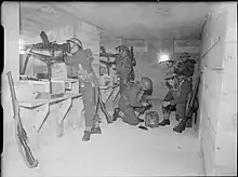British soldiers man machine guns inside a concrete bunker.