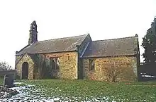A simple stone chapel seen from the south with a west bellcote