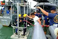 Royal Brunei Navy divers are lowered from rescue and salvage ship USNS Safeguard (ARS-50) during familiarisation dives on 8 August 2005.